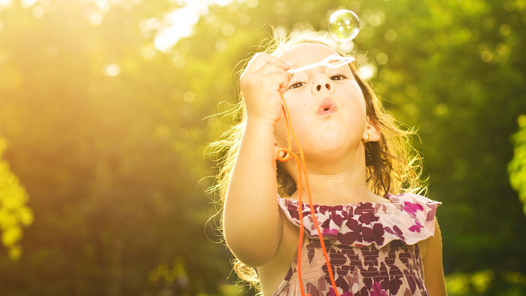 Little girl in park blowing bubbles