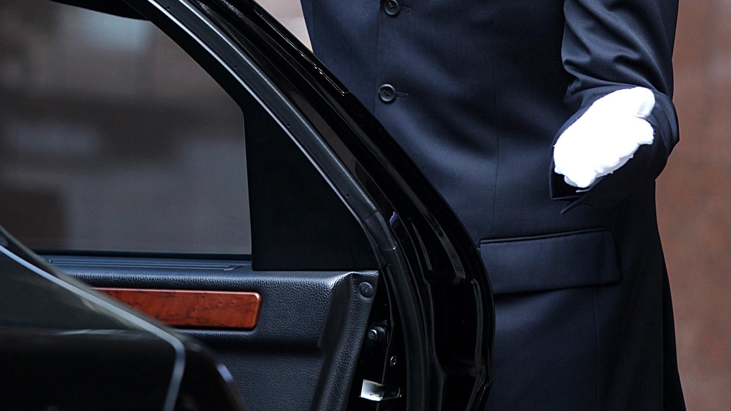 White formal gloved uniformed hand opening car door
