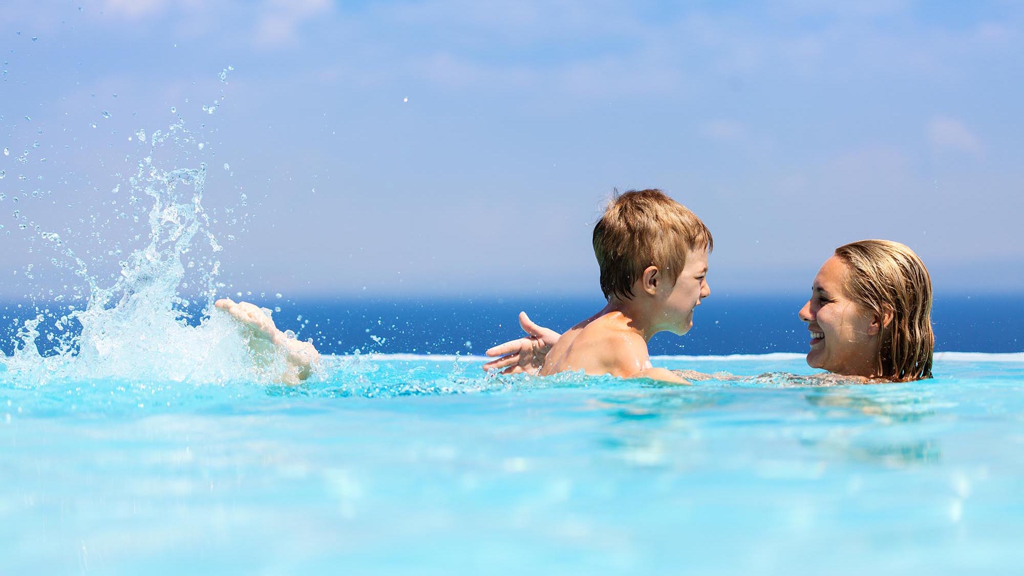 Mother and child swimming in infinity pool