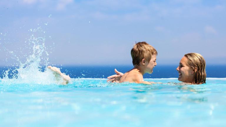 Mother and child swimming in infinity pool