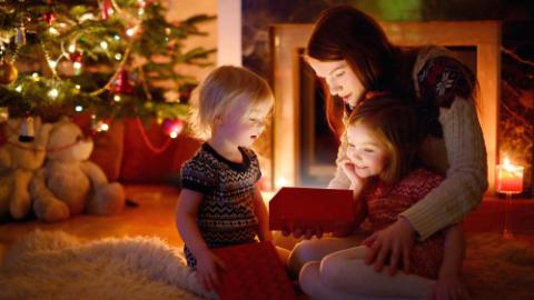 mother and her two little daughters opening a magical Christmas gift