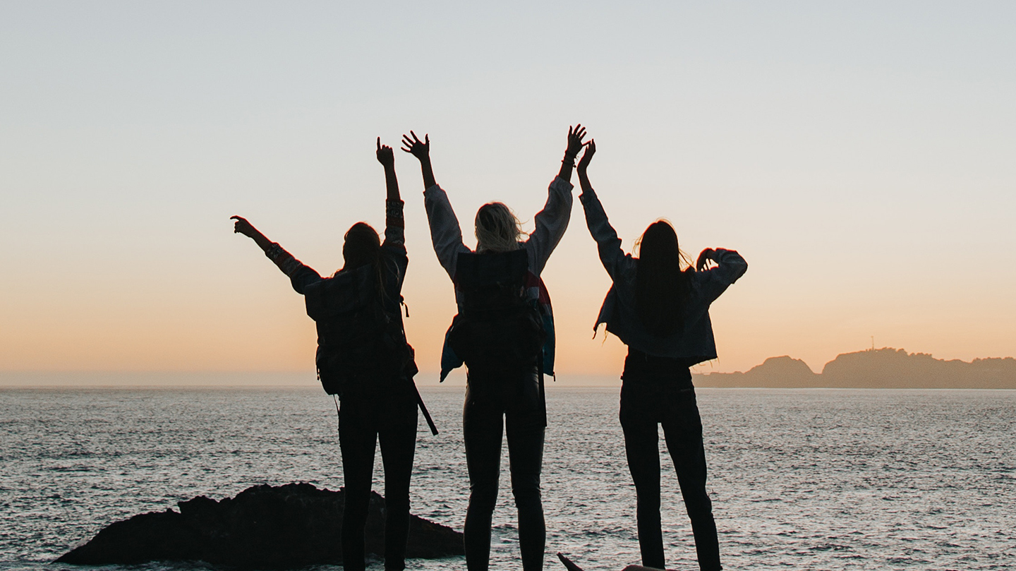 cheering woman open arms to sunrise at seaside